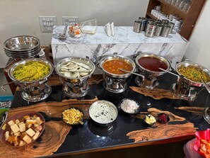 A buffet table with various food items and condiments. - Mudra Villa & Resort (Nagaon)