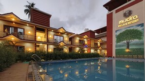 A multi-story building with a swimming pool, balconies, and a sign for Mudra Villa & Resort. - Mudra Villa & Resort (Nagaon)