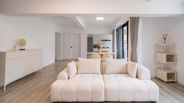 Een moderne woonkamer met een grote witte bank, een kleine tafel en een witte console.