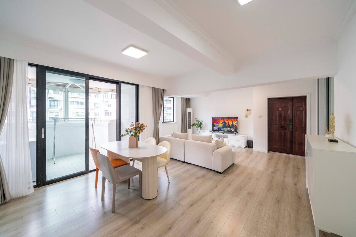 Een moderne woonkamer met een bank, een eettafel met stoelen en een televisie.