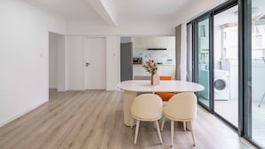 Een moderne keuken met witte kastjes, een ingebouwde oven en een wasmachine zichtbaar door een glazen deur.