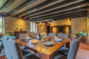 A dining area with a wooden table set for six, stone walls, and exposed beams. - Laperletta beautiful French villa in the Dordogne with stunning views (Saint-Pompon)
