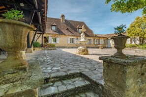 A courtyard with stone flooring, a fountain, and a building with a tiled roof. - Laperletta beautiful French villa in the Dordogne with stunning views (Saint-Pompon)