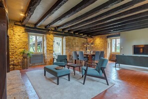 A rustic interior with exposed wooden beams, stone walls, and a stone floor. There are several chairs and a table, suggesting a dining area. - Laperletta beautiful French villa in the Dordogne with stunning views (Saint-Pompon)