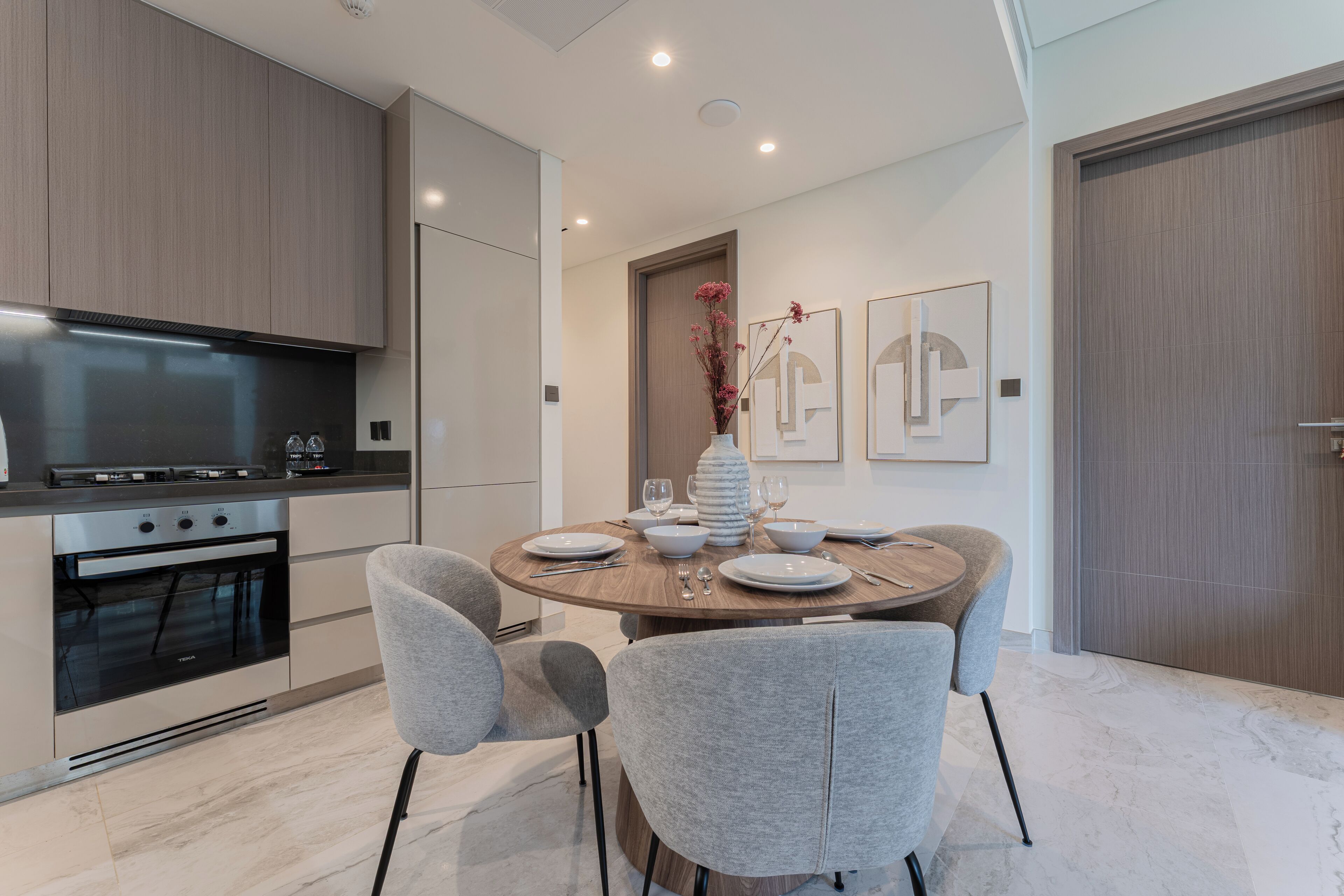 A modern kitchen with a built-in oven and a dining area with a round table and four chairs.