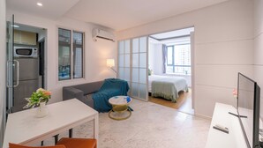 Una habitación de hotel moderna con comedor, kitchenette y un amplio ventanal corredera que da a un balcón.