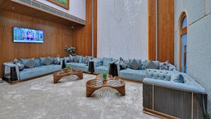 Un interior moderno con un sofá modular, mesas de centro de madera y un televisor de pantalla plana.