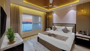 Una habitación de hotel moderna con una cama grande, un ventilador de techo, una mesita de noche y un ventanal con vistas.