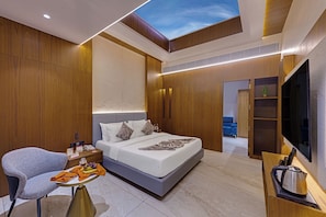 Una habitación de hotel moderna con cama, zona de estar, televisor y tragaluz.
