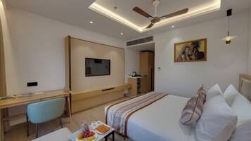 A hotel room with a bed, desk, chair, and a painting on the wall.