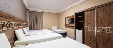A hotel room with two beds, a TV, a wardrobe, and a small table.