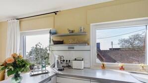 A kitchen with a coffee maker, toaster, and a window with a view of a building.