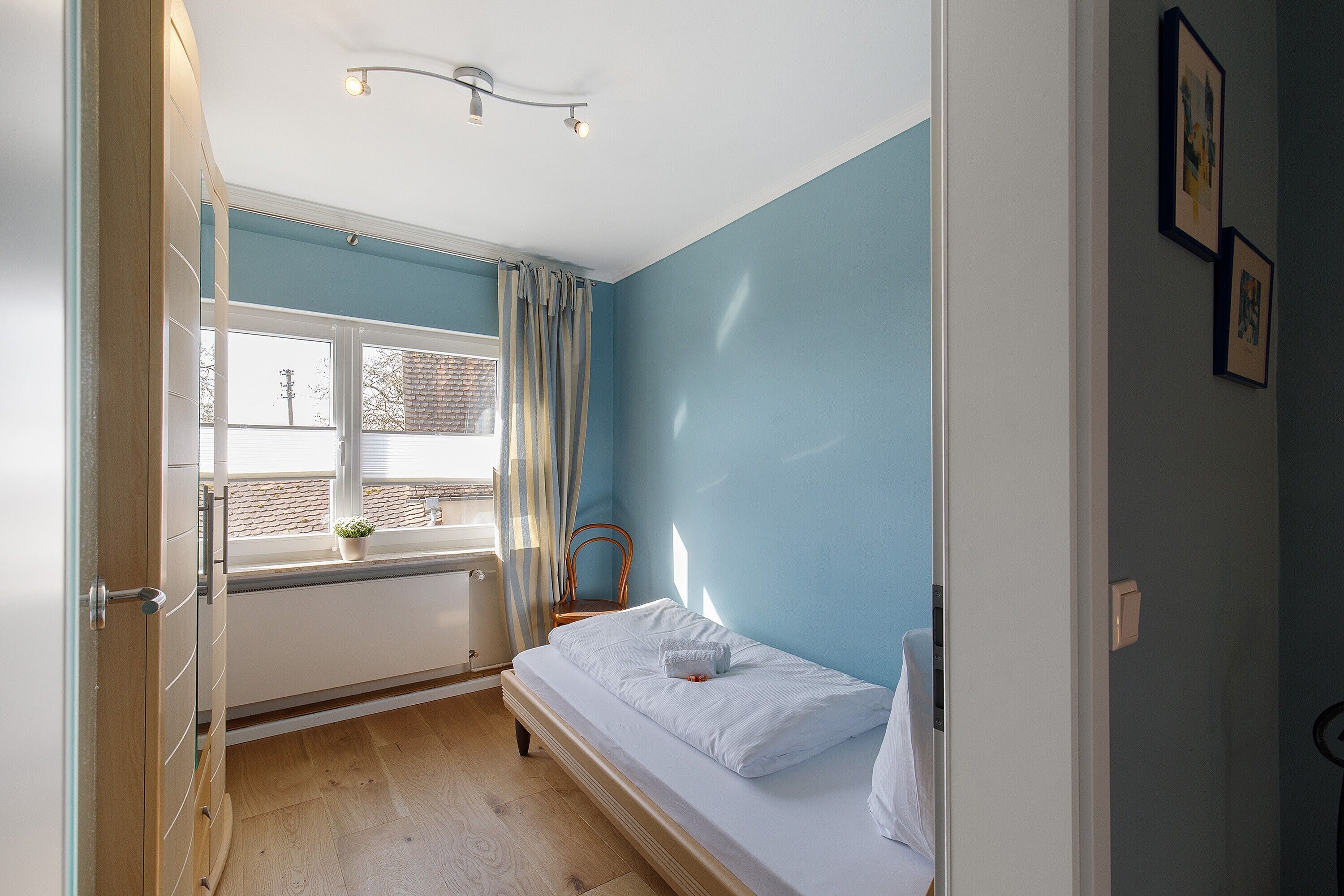 Et værelse med en seng, et vindue med gardiner, en radiator og en vægmonteret lampe.