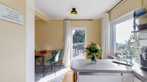 A modern kitchen with a dining area, a view through the window, and a sign on the wall.