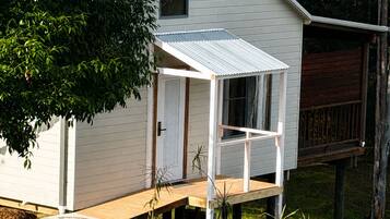 A small white house with a porch, surrounded by trees and a hammock.