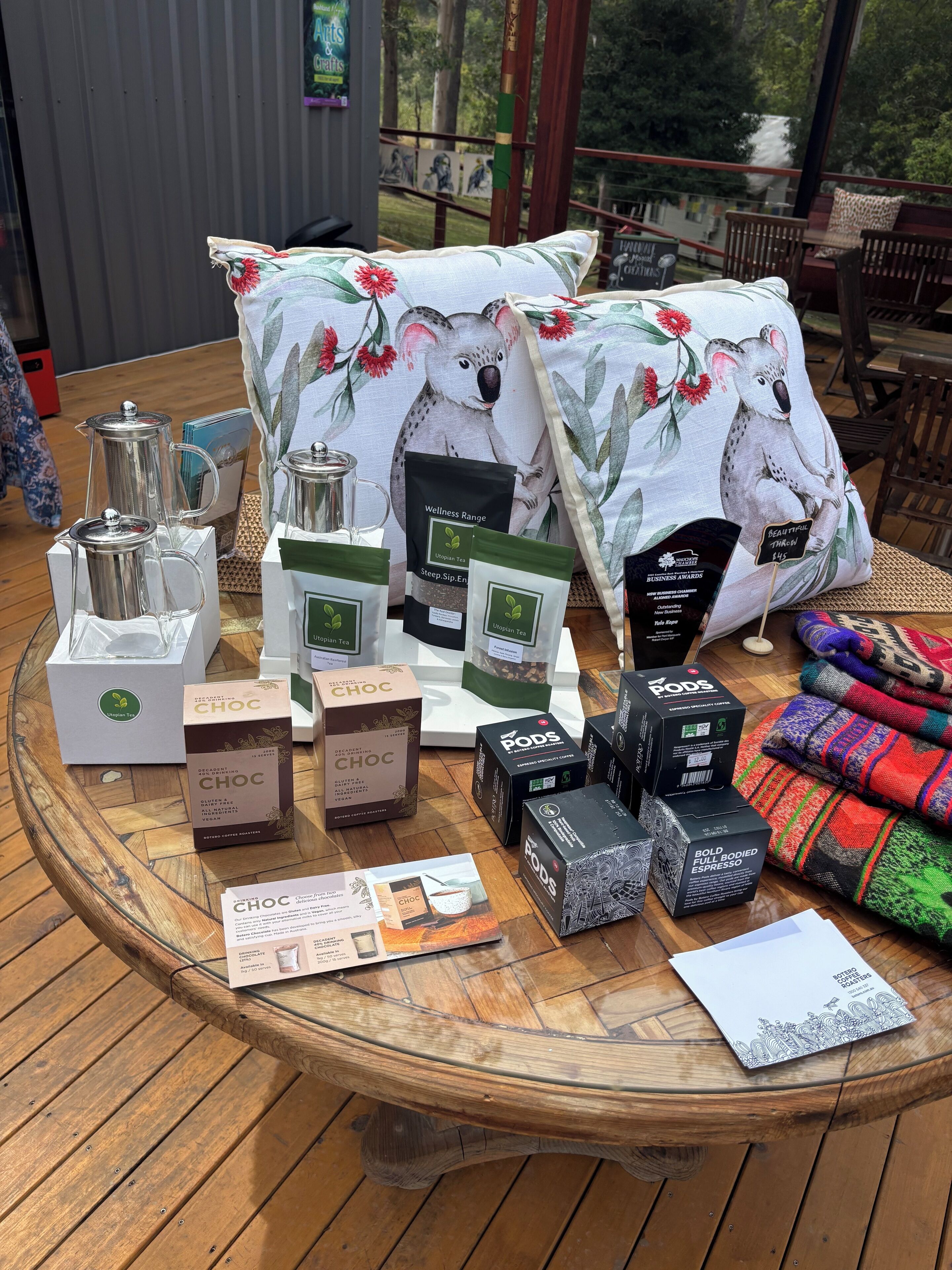 A display table with various products including bags of Utopian Tea, a coffee maker, and a kettle.