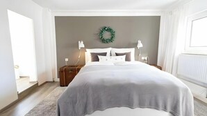 Une chambre à coucher avec un lit, une table de chevet, une lampe, une prise de courant, un radiateur et une guirlande décorative accrochée au mur.