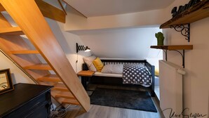 Une chambre à coucher comprenant un lit, un bureau, une chaise, un radiateur, une étagère avec des livres, une lampe et un escalier.