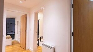 Un couloir doté d’un plancher en bois, d’un radiateur et d’une porte donnant sur une chambre.