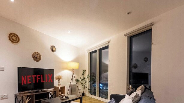 Un salon avec un canapé, une table basse, un téléviseur et une lampe.