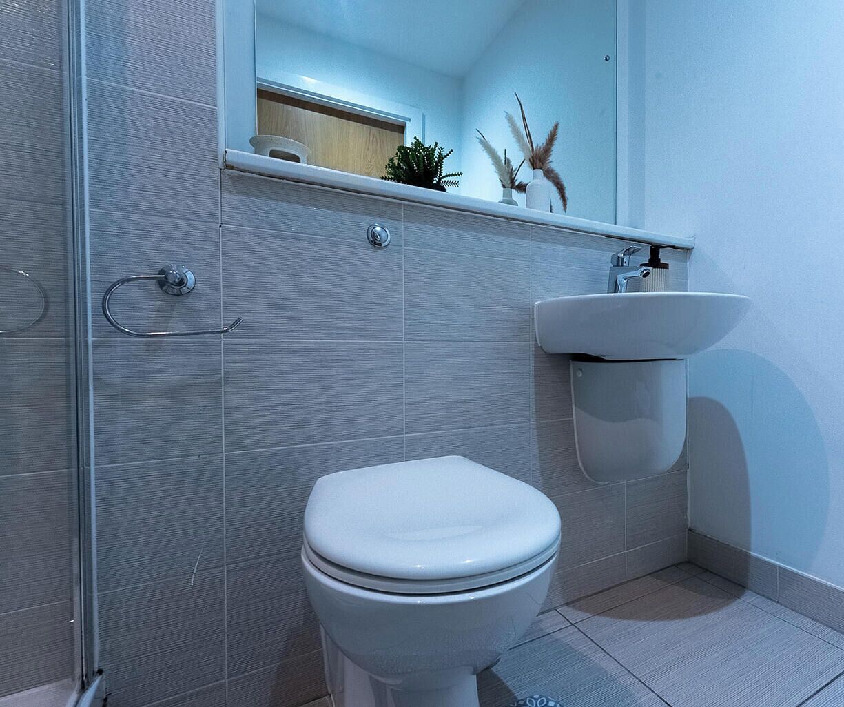 Une salle de bain moderne avec des toilettes, un lavabo et un miroir.