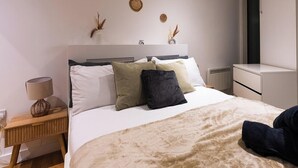 Une chambre à coucher avec un lit, une table de chevet, une lampe et des éléments décoratifs sur les murs.