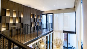 Un interior moderno con un entrepiso, una escalera con barandilla de metal e iluminación colgante.