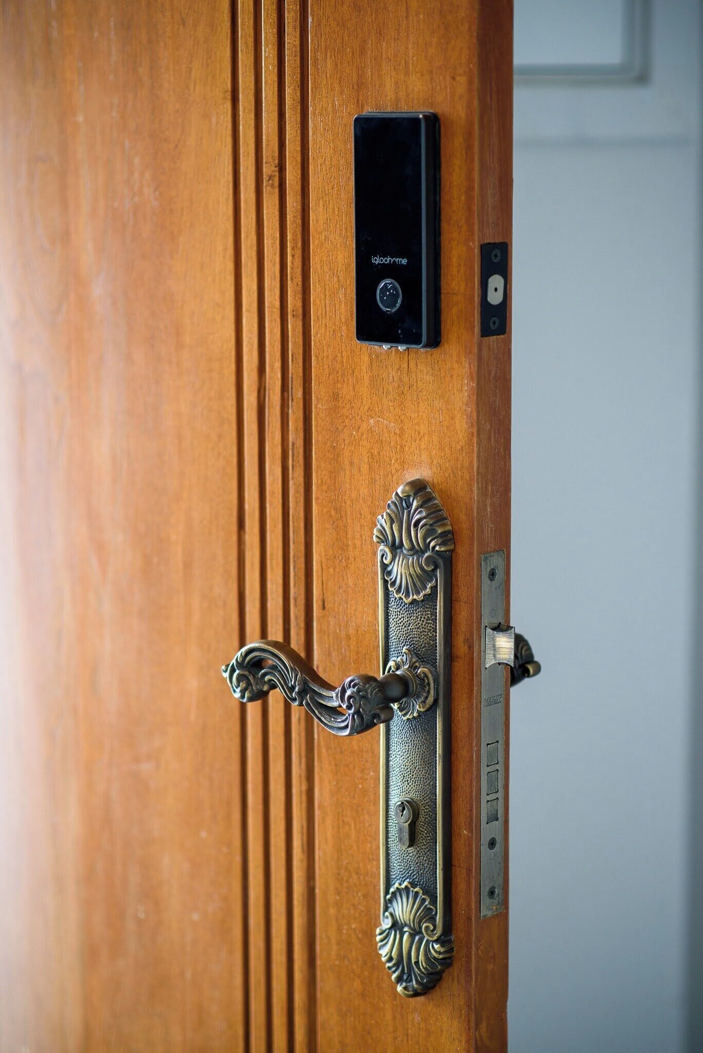 Une porte en bois dotée d’une poignée métallique traditionnelle et d’une serrure électronique moderne.