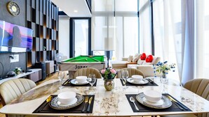Un comedor moderno con mesa de billar, televisor montado en la pared y sofá con cojines rojos.