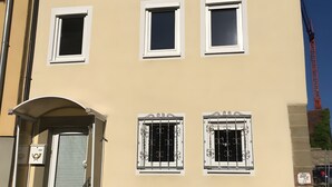 A multi-story building with a beige facade, multiple windows with white frames, a gated entrance, and a staircase leading to the entrance. - Apartment 'Snug' with Wi-Fi (Neuenstein)