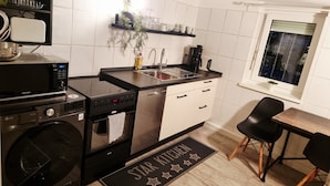 A modern kitchen with a dishwasher, oven, and a sink. There is a window with a view of the outside. - Apartment 'Snug' with Wi-Fi (Neuenstein)