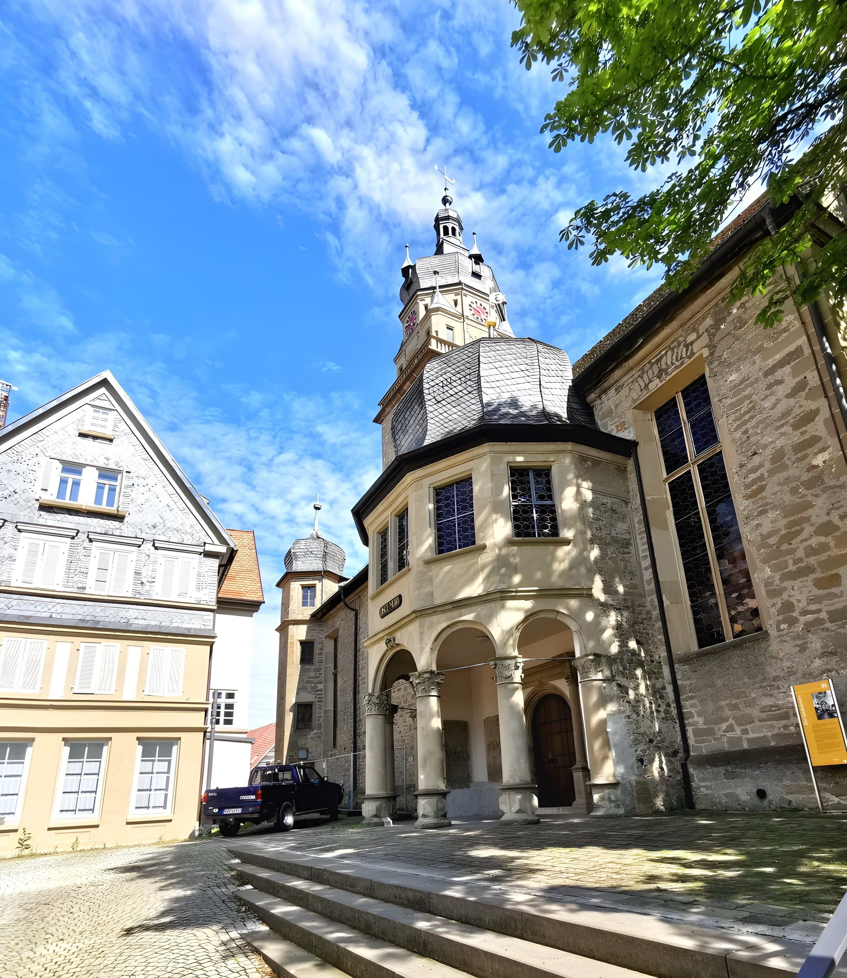 Un edificio storico con una torre dell'orologio, finestre ad arco e una strada acciottolata.