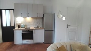 A compact kitchen with white cabinets, a stainless steel refrigerator, and a tiled backsplash. - Authentique Bouquet (Le Mans)