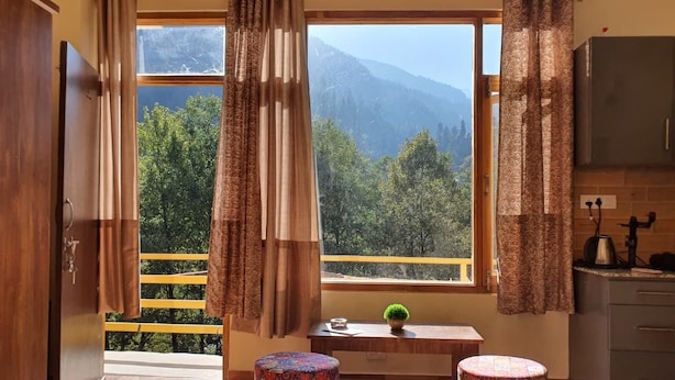 A kitchen with a view of mountains, two patterned stools, and a small table with a plant. - Alooma Valley View Stays (Manali)