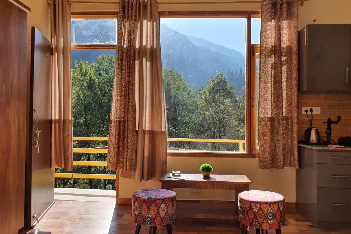 A kitchen with a view of mountains, two patterned stools, and a small table with a plant.