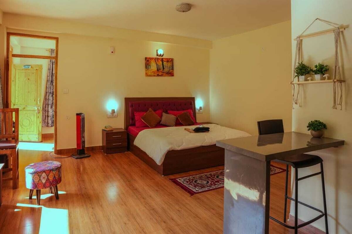 A bedroom with a bed, bedside tables, a desk, and a chair.