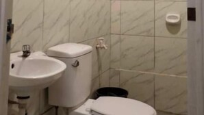 A small bathroom with a toilet, sink, and a mirror. - WJV INN JUGAN (Liloan)