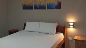 A bedroom with a bed, two nightstands, and three wall-mounted paintings. - WJV INN JUGAN (Liloan)