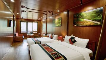 A hotel room with two beds, a desk, a chair, and a large window.