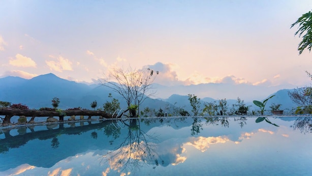A tranquil infinity pool with a clear view of mountains and a sunset. - Muong Hoa River View Homestay (Ta Van)