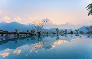 A tranquil infinity pool with a clear view of mountains and a sunset.
