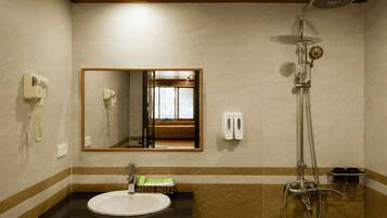 Baño con lavamanos, espejo, ducha y teléfono en la pared.