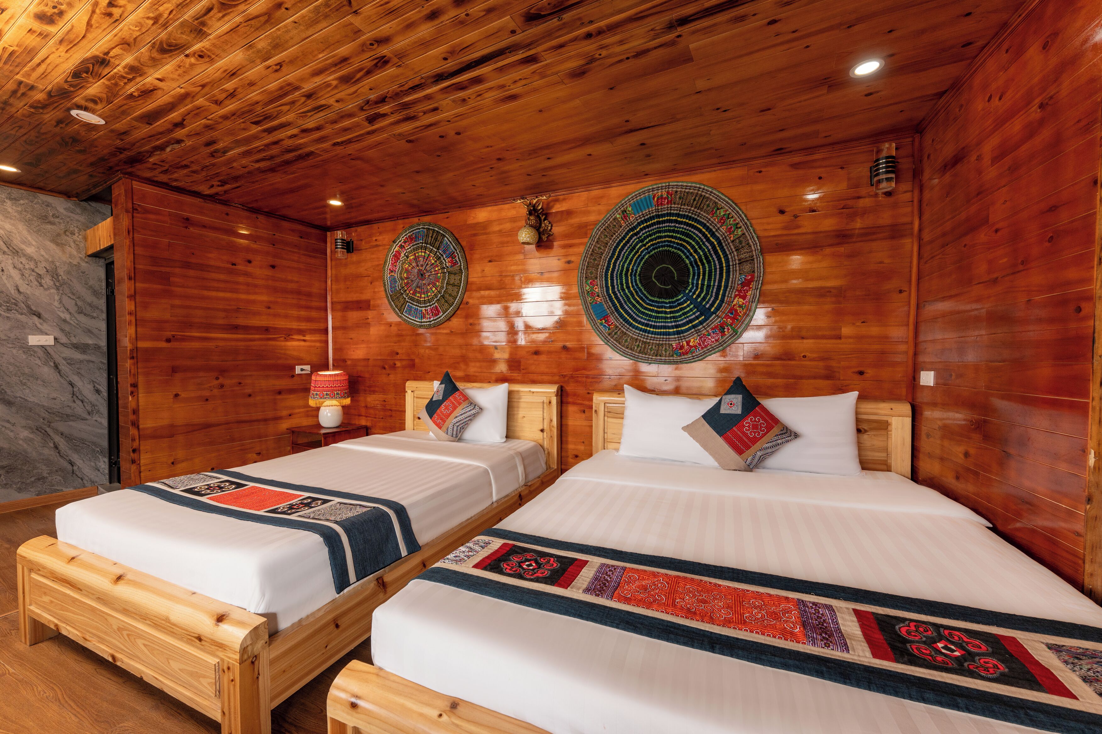 Quarto com duas camas de madeira, cada uma com colchão branco e colcha estampada.