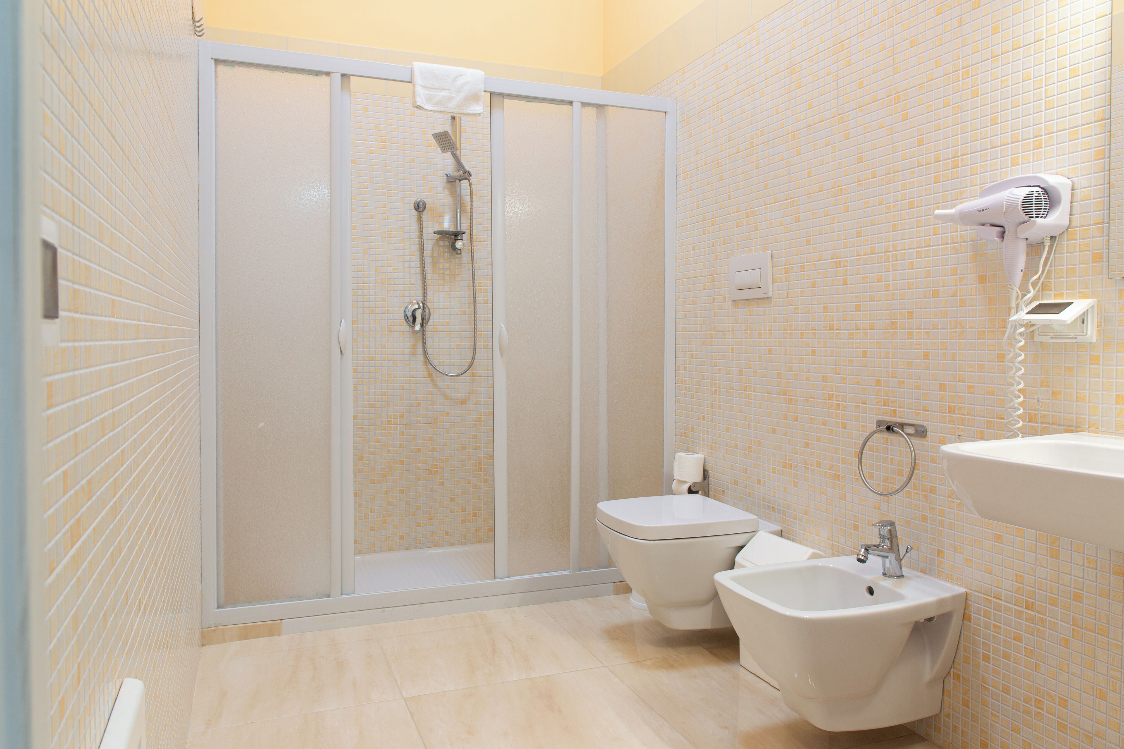 Ein Badezimmer mit Duschkabine, Toilette, Bidet und Waschbecken.