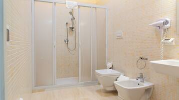 Ein Badezimmer mit Duschkabine, Toilette, Bidet und Waschbecken.