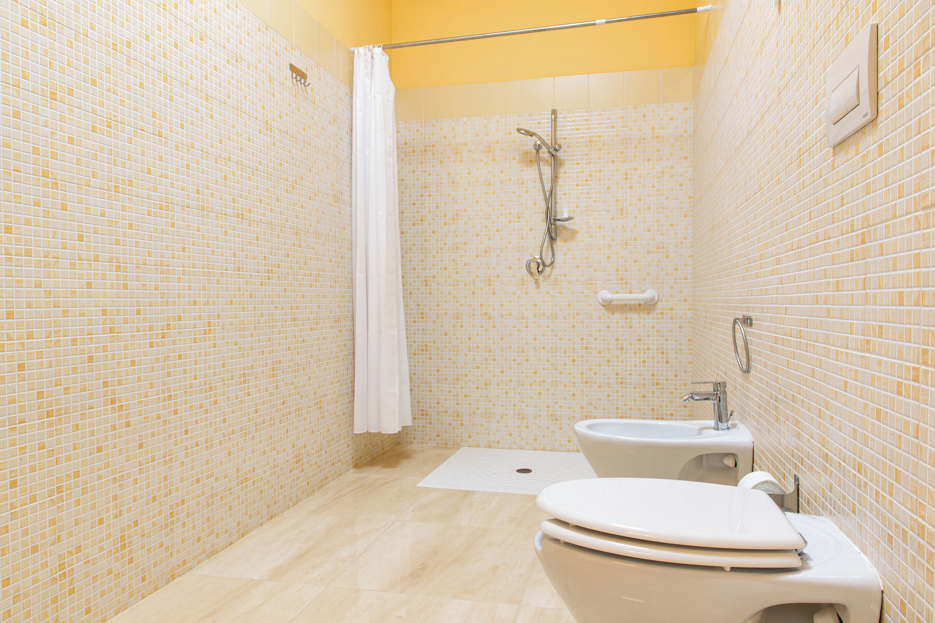 A small, tiled bathroom with a shower, toilet, and sink.