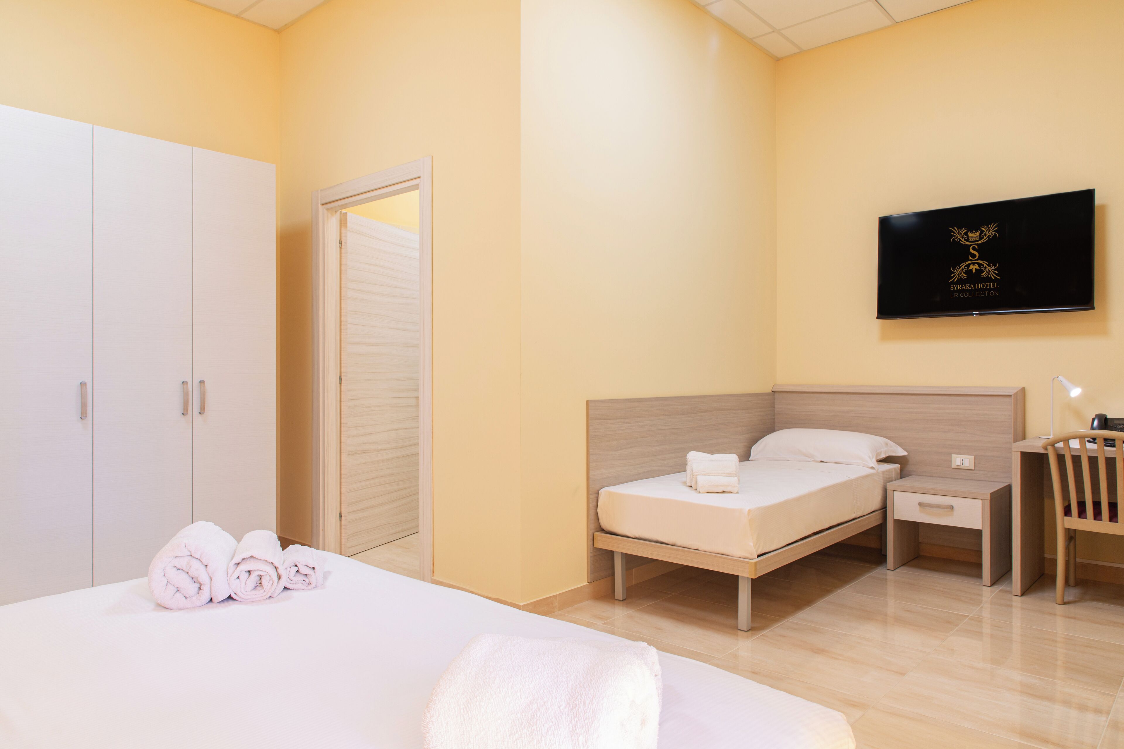 Une chambre d’hôtel équipée d’un lit, d’un bureau, d’une chaise, d’une télévision et d’une armoire.