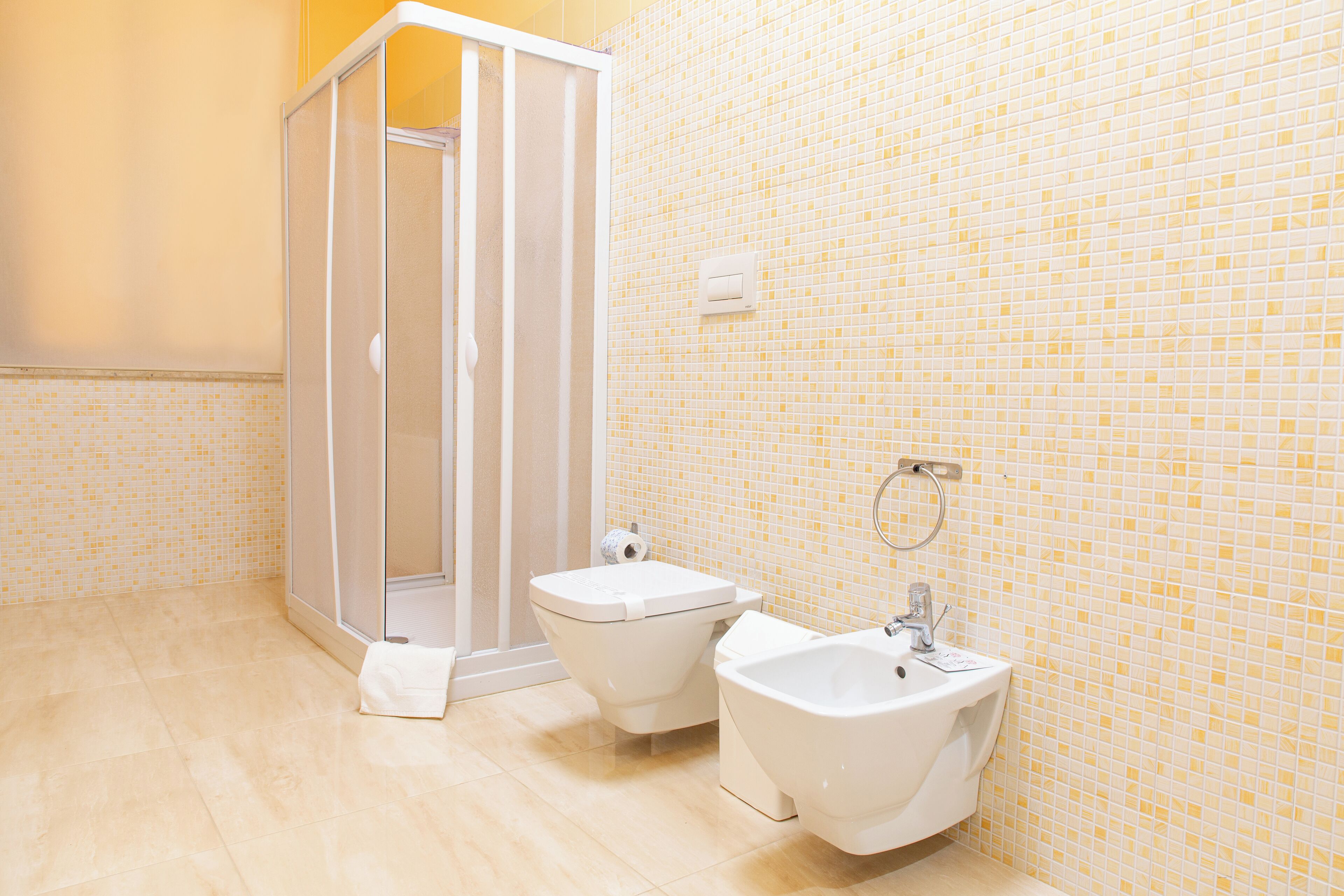 A bathroom with a shower, two bidets, and a sink.