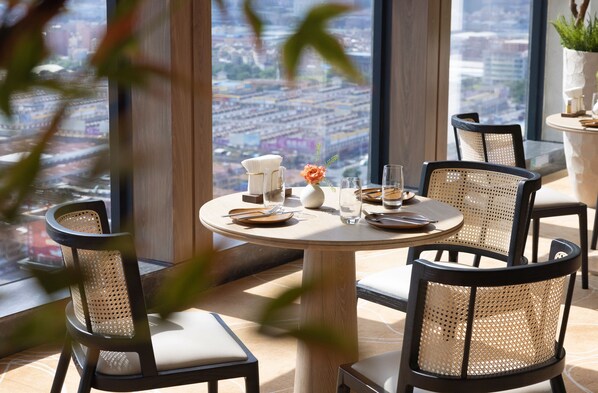 Un espace repas avec une table ronde, des chaises et une vue sur la ville.