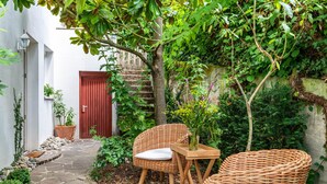 A stone pathway leading to a red door, surrounded by lush greenery and a wicker table with chairs. - Apartment 'Romantica' with Lake View, Private Terrace and Wi-Fi (Sipplingen)